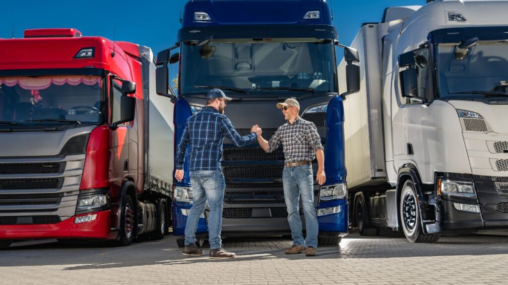 Two Drivers Shaking Hands in Front of a Semi Truck in a Lot