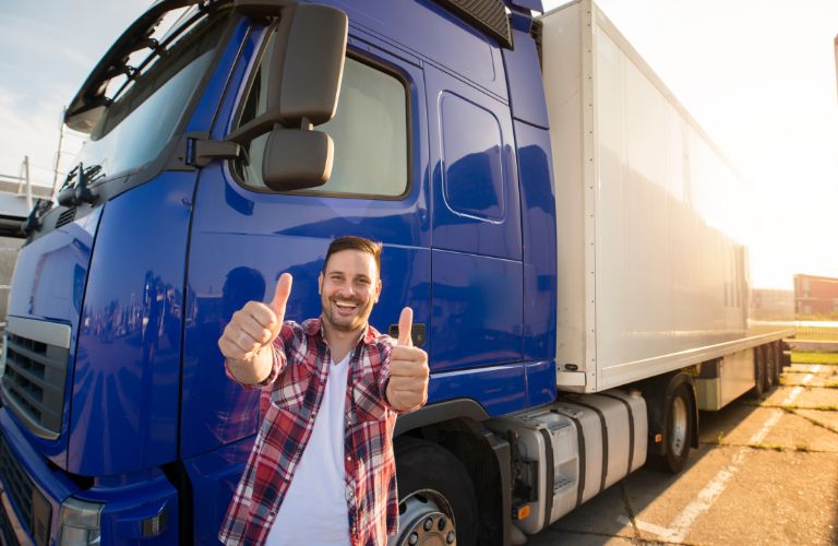 Truck Driver in Front of Blue Truck Giving Thumbs Up