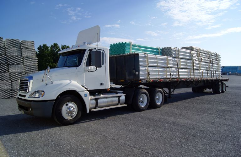 White Truck with Flatbed Full of Pipes
