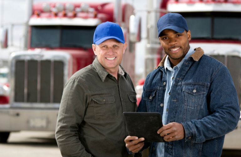 Two Truck Drivers Standing in a Lot with Trucks