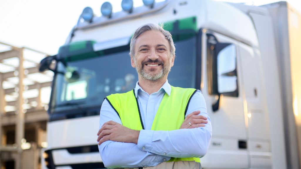 Truck Driver in Bright Yellow Vest in Front of White Semi Truck